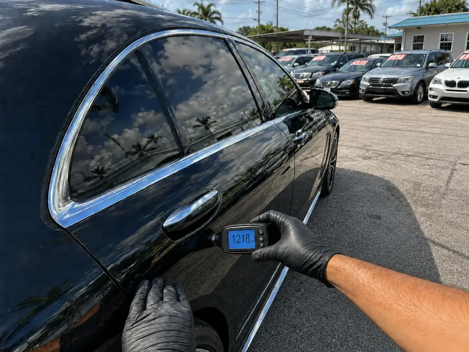 Inspector midiendo pintura en un vehículo del lote